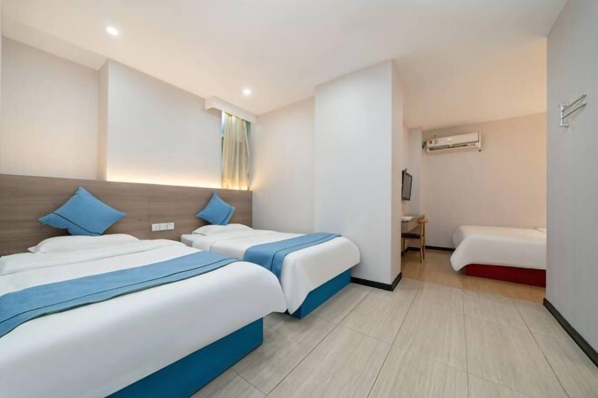 A hotel room with two beds, a desk, and a TV.