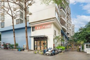 A multi-story building with a sign indicating a service area, a gated entrance, and parked scooters. - Geziwei Hotel Nanning Wuliting (Nanning)
