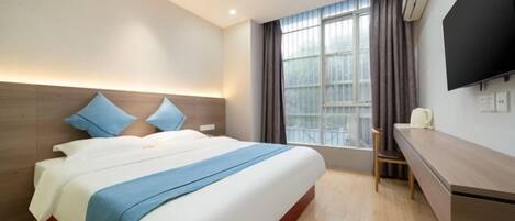 Une chambre d’hôtel avec un grand lit, un bureau, une chaise, une télévision et une fenêtre avec des rideaux.