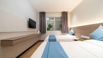 Een hotelkamer met een bed, nachtkastje, televisie en een raam met gordijnen.
