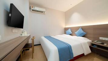 Een moderne hotelkamer met een bed, nachtkastje en een wandgemonteerde flatscreen televisie.