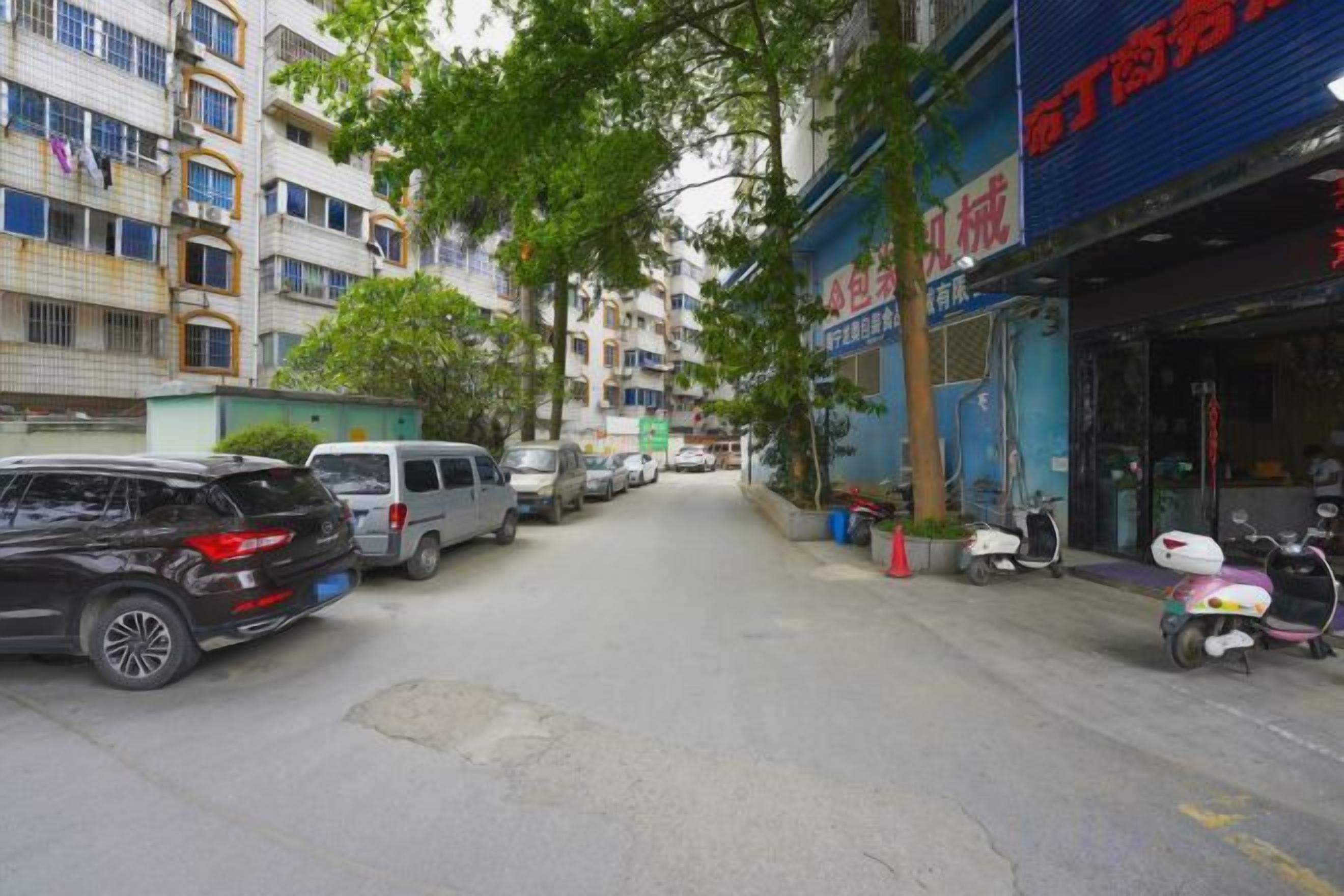 Una calle con coches estacionados y un edificio con un letrero en un idioma extranjero.