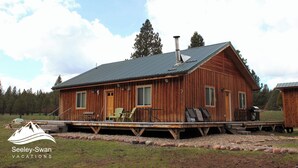 A wooden cabin with a porch, a chimney, and outdoor seating.