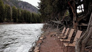 A riverside bench area with a row of benches and a path leading to the water.
