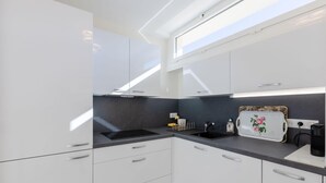 A modern kitchen with white cabinets, a black countertop, and a skylight. - Luxurious 2-room Apartment in Palm Beach (Cannes)