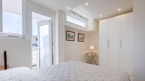 A bedroom with a large bed, a wardrobe, a small table with a lamp, and a skylight. - Luxurious 2-room Apartment in Palm Beach (Cannes)