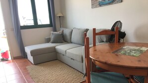 Una sala de estar con un sofá gris, una mesa de comedor de madera y un tapete estampado.