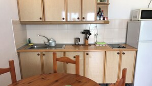 Una cocina con armarios de madera, un lavaplatos, un microondas y un refrigerador. Hay una mesa de comedor de madera con un mantel individual.