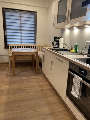 A modern kitchen with a wooden bench, a coffee maker, and an oven. - Cozy vacation apartment in a central location (Dissen am Teutoburger Wald)