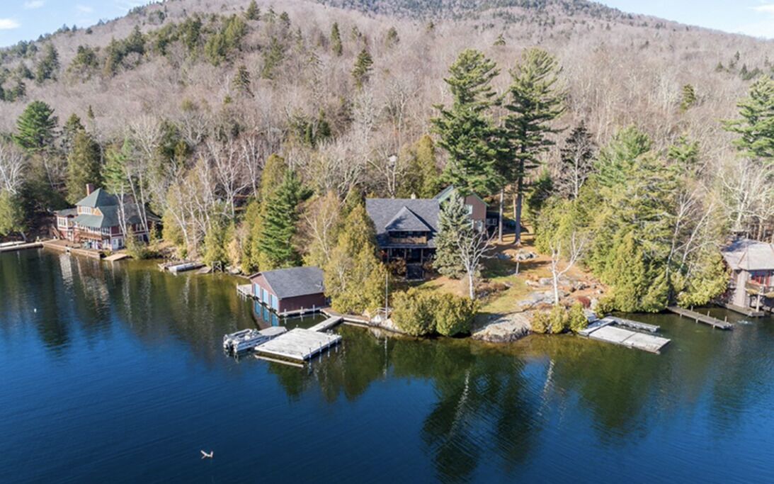A lakeside property with multiple cabins, docks, and a docked boat.