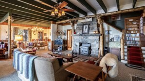 A cozy lodge with a stone fireplace, wooden furniture, and a bookshelf.