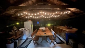 A cozy kitchen with wooden benches, a dining table, and string lights.