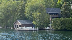 A lakeside cabin with a dock, surrounded by dense forest.