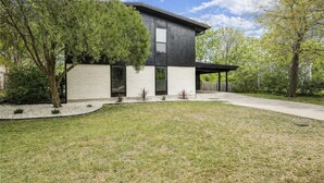 A modern two-story house with a flat roof, large windows, and a covered porch. - Gig`em on Glade-Spacious 5BR Home w/ Huge Backyard near TAMU (College Station)