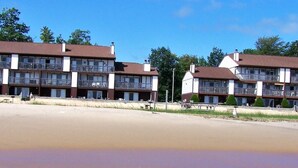 Ein Strandhotel mit mehreren Balkonen und einem sandigen Strand im Vordergrund.