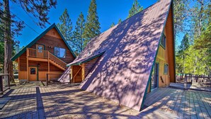 A cabin with a wooden exterior, a balcony, and a steeply pitched roof.