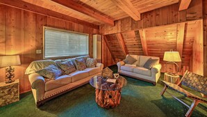 A cozy, wooden-furnished living room with two sofas, a coffee table, and a lamp.