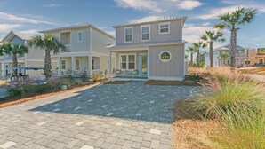 A two-story residential building with a covered porch and a landscaped driveway.