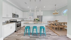A modern kitchen with white cabinets, stainless steel appliances, and a central island with bar stools.