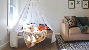 A room with a hanging chair, a sofa, and a patterned rug. - City Oasis - Historic Blackrock- Pets and Parking (Buffalo)