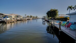A marina with docked boats, a swimming pool with colorful lounge chairs, and a clear sky. - 50’ of Dock for your boats. Hot tub, Boatlift, walk 2 restaurants Xtra parking.  (Matlacha)