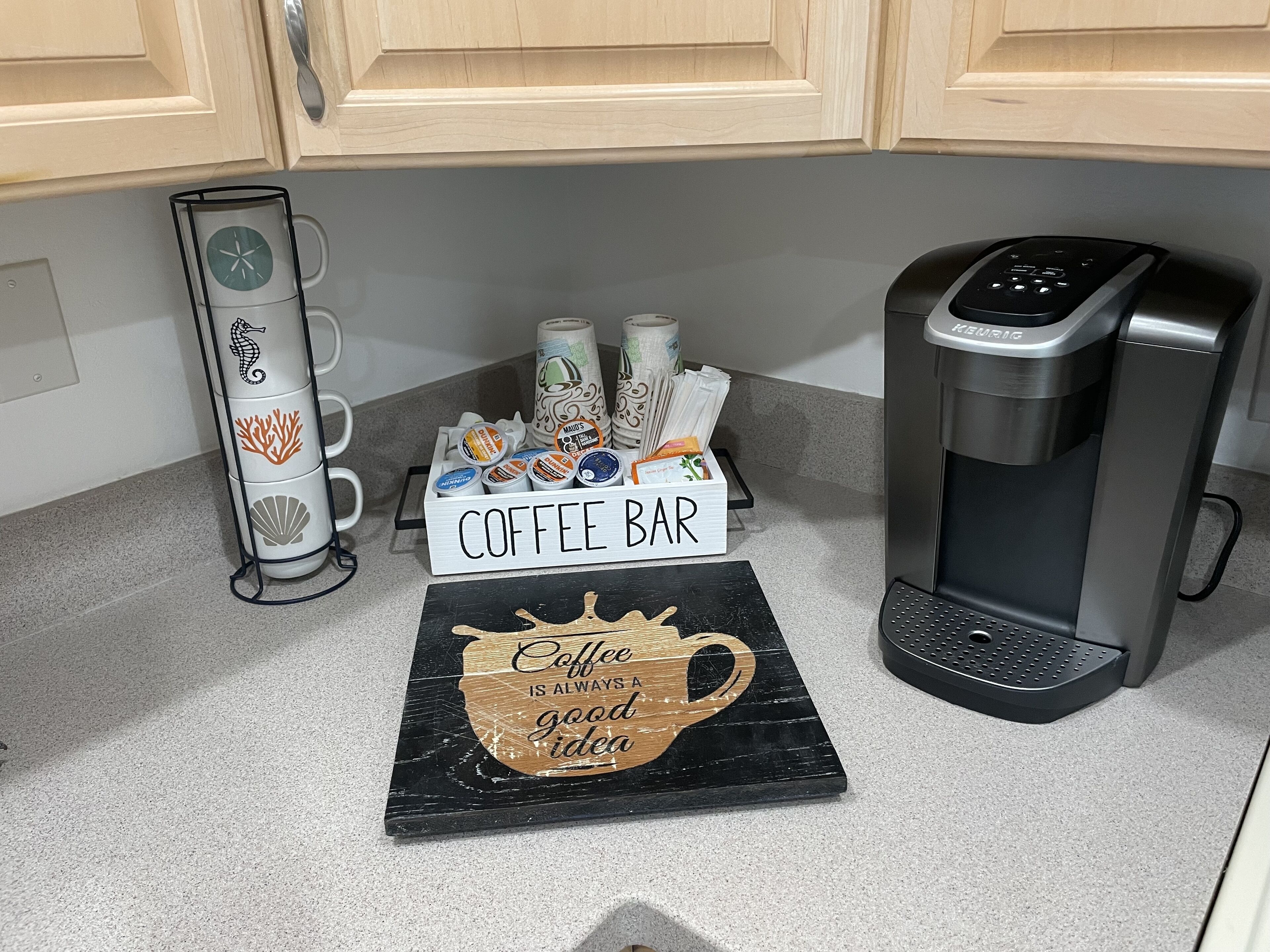 A coffee bar setup with a coffee maker, a coffee mug holder, and a coffee pod display.