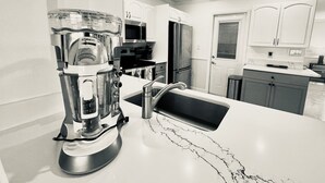 A kitchen with a coffee maker, microwave, refrigerator, and a sink with a marble countertop. - 50’ of Dock for your boats. Hot tub, Boatlift, walk 2 restaurants Xtra parking.  (Matlacha)