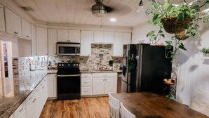 A kitchen with white cabinets, a black refrigerator, a microwave, and a wooden countertop. - Charming Palm Beach Home Close to Beaches (Tequesta)
