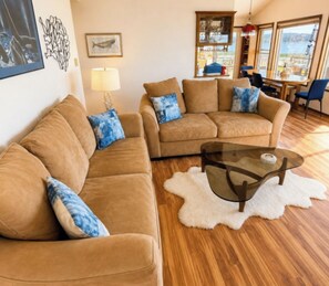 A living room with two sofas, a glass coffee table, and a view of the outdoors.