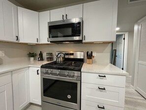A modern kitchen with white cabinets, a stainless steel stove, and a microwave above it.