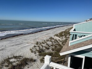 A beach view with a house overlooking the ocean.