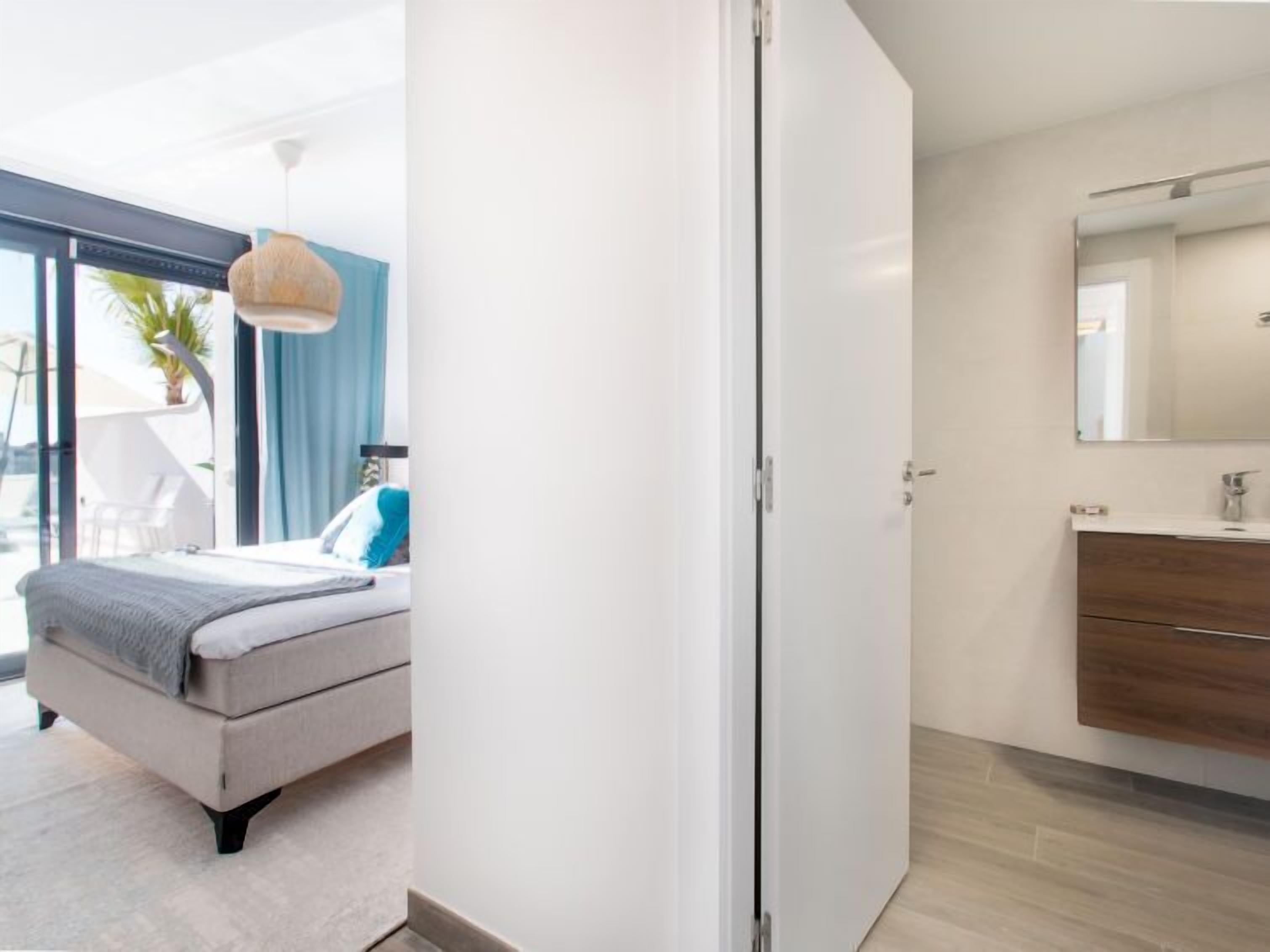 Une chambre à coucher moderne avec un lit, une table de chevet, une lampe suspendue et une vue sur le balcon.