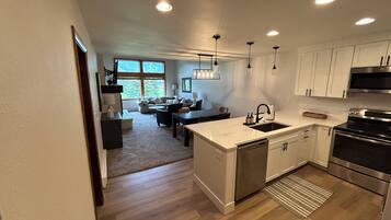 Una cocina moderna con gabinetes blancos, electrodomésticos de acero inoxidable y una isla central con pileta.