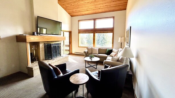 A living room with a fireplace, a sofa, a coffee table, and a television mounted on the wall. - Ultimate Beaver Creek Condo: 3 BED - 3 BATH condo SLEEPS 8 with 6 beds (Avon)