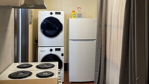 A compact kitchen with a stove, a washing machine, and a refrigerator. - Spacious 1-bedroom in Oakland with AC (Oakland)