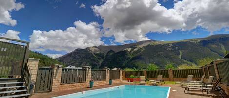 Una piscina con sillas de descanso y vistas a las montañas.