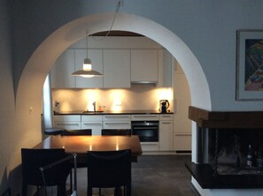 A modern kitchen with white cabinets, a wooden dining table, and black chairs.
