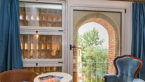 A room with a large arched window, wicker furniture, and a view of a brick building and greenery outside. - Beautiful apartment in villa for 10 guests with WIFI, private pool, TV, patio and pets allowed (Monsummano Terme)