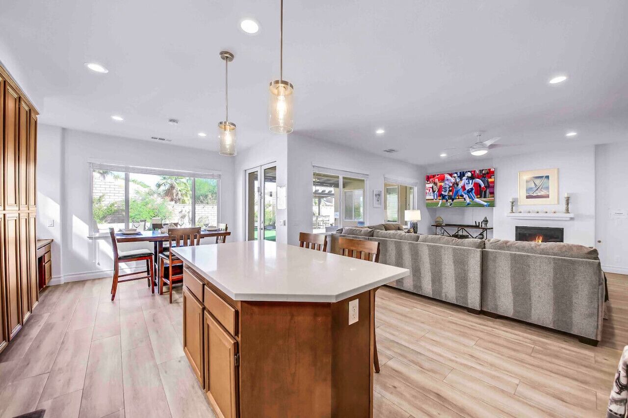 A spacious kitchen with a large island, wooden cabinets, and pendant lighting.