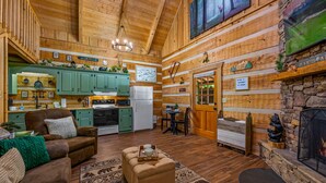 A log cabin interior with a living room, kitchen, and dining area.