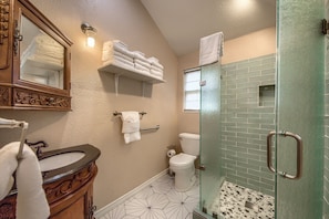 A bathroom with a vanity, a toilet, a glass shower enclosure, and a towel rack with folded towels. - Ponderosa Country Haus Prd 2495 2 Bedroom Home by RedAwning (New Braunfels)