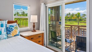 Quarto com uma grande porta de correr de vidro que dá para uma varanda com vista para um campo de golfe.