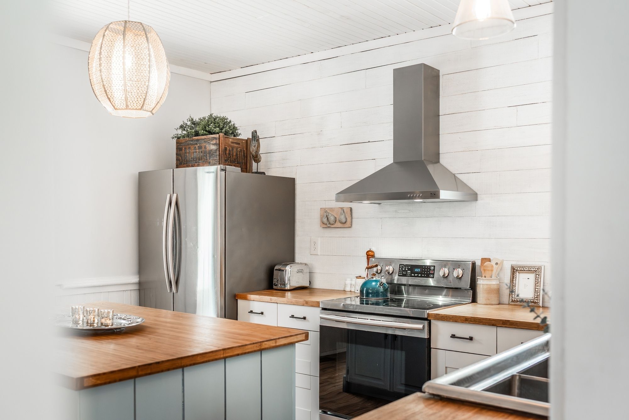 Una cocina moderna con un refrigerador de acero inoxidable, un horno empotrado y una campana extractora.