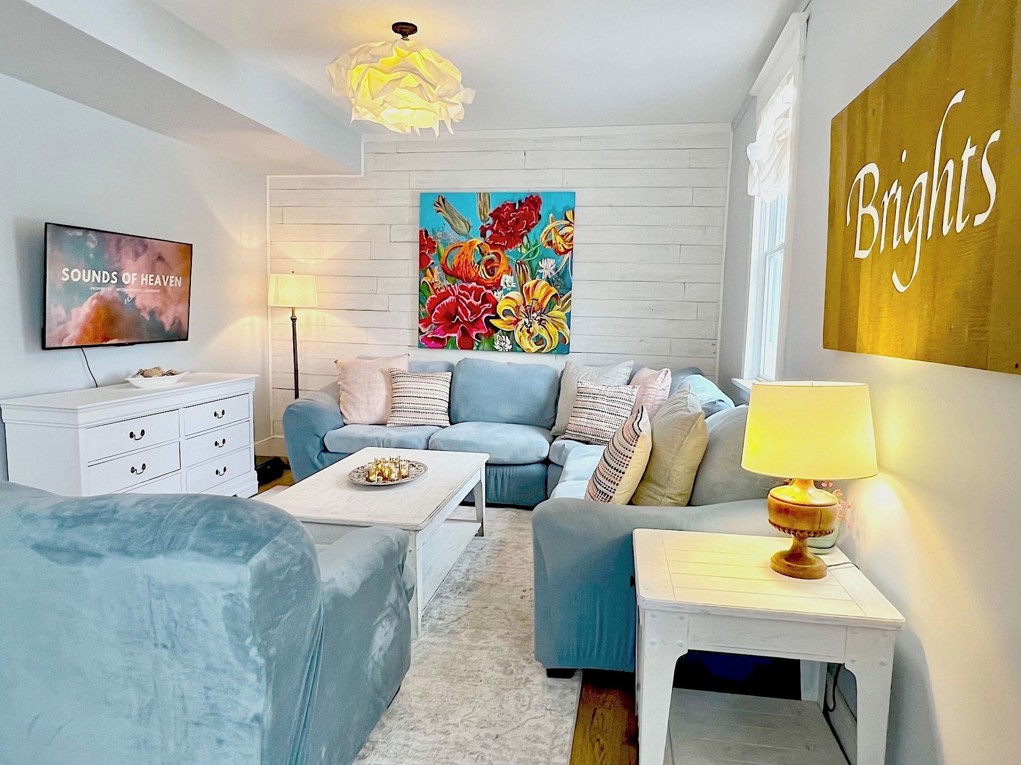 A modern living room with a sofa, a coffee table, a TV, and a painting on the wall.
