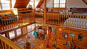 A multi-level wooden cabin with a loft bedroom, a dining area, and a kitchen. - Norris Lakefront Retreat- Hot Tub, Firepit, Dock. Direct Lake Front. Sleeps 20 (LaFollette)
