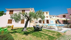 A building with a swimming pool, outdoor seating, and a tree. - Cosy apartment for 6 people with WIFI, pool, A/C, terrace and pets allowed (Orosei)