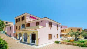 A pink building with a sign reading "Residence." It features a tiled roof, multiple windows, and a small balcony. - Cosy apartment for 6 people with WIFI, pool, A/C, terrace and pets allowed (Orosei)