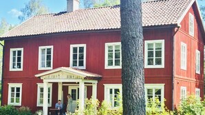 A red two-story building with a central entrance and a porch.