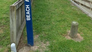 A wooden fence with a sign indicating beach access.