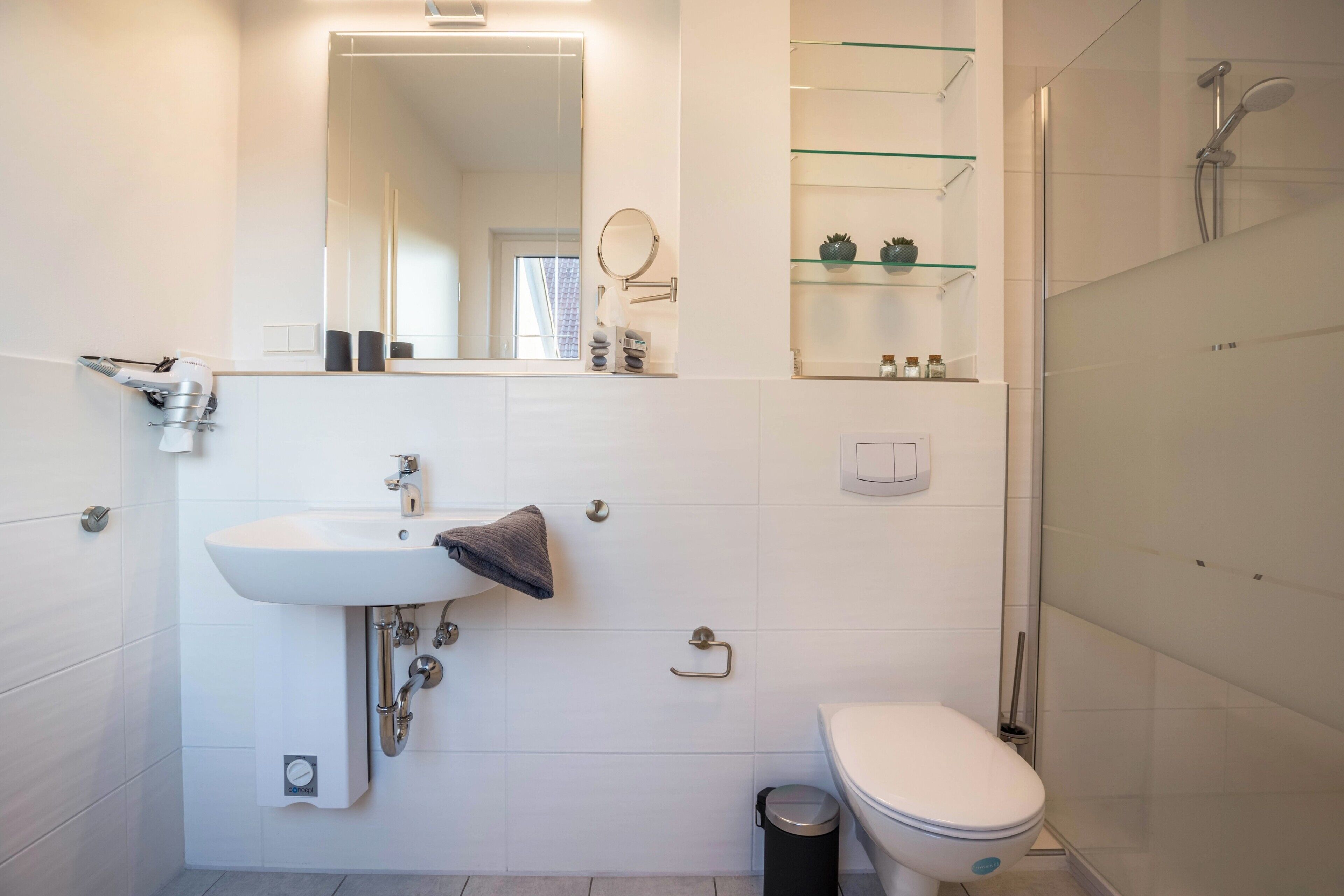 Ein modernes Badezimmer mit Waschbecken, Spiegel, Toilette und Dusche.